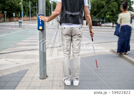 Midsection of blind man with white cane at pedestrain crossing in city. 59922822