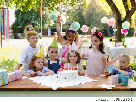 Down syndrome child with friends on birthday party outdoors in garden. Down syndrome child with friends on birthday party outdoors in garden. 59922851
