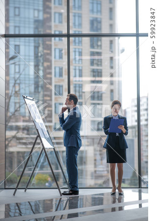 Businessman looking at smart board while business lady making some notes Businessman looking at smart board while business lady making some notes 59923847