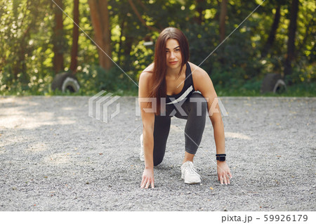 Sports girl in a black top training in a summer park 59926179