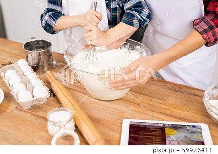 Hands of young woman holding bowl while her little son whisking eggs with flour 59926411