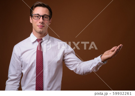Young handsome businessman wearing eyeglasses against brown back 59932261