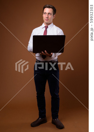 Young handsome businessman against brown background Young handsome businessman against brown background 59932303