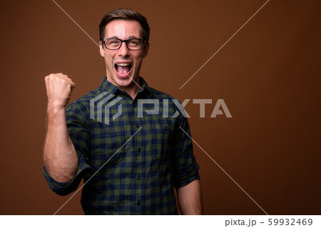 Young handsome man wearing eyeglasses against brown background Young handsome man wearing eyeglasses against brown background 59932469