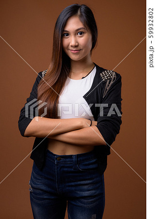 Young beautiful Asian woman against brown background Young beautiful Asian woman against brown background 59932802