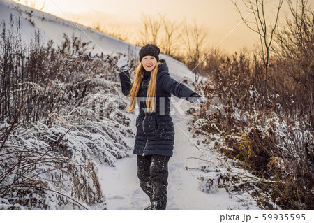 winter girl throwing snowball at camera smiling happy having fun outdoors on snowing winter day 59935595
