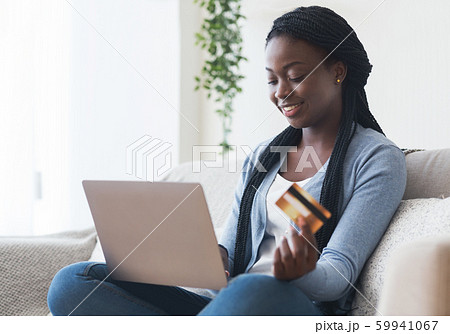 Black Girl Using Laptop and Credit Card Purchasing Things Online 59941067