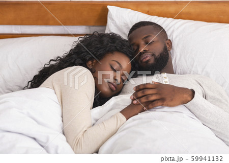 Afro couple sleeping in comfortable bed at home Afro couple sleeping in comfortable bed at home 59941132