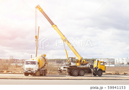 Installation and construction of lighting lamps on the new road using a truck crane and cement truck, the sun, copy space, building Installation and construction of lighting lamps on the new road using a truck crane and cement truck, the sun, copy space, building 59941153