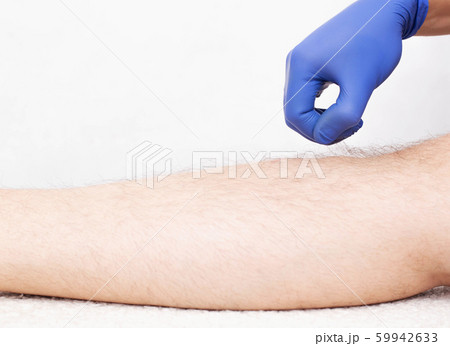 Doctor beautician holds the hair in the hand of a man on the leg, preparing for laser hair removal, white background, copy space 59942633