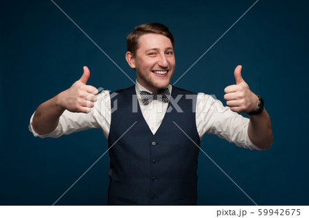 Positive young man in formal suit shows thumbs up Positive young man in formal suit shows thumbs up 59942675