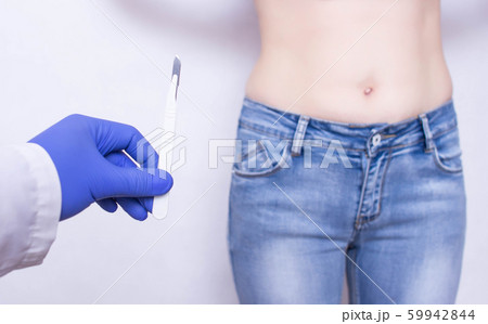 The doctor holds a scalpel on the background of the abdomen of the girl. The concept of surgery for inflammation of appendicitis, medical The doctor holds a scalpel on the background of the abdomen of the girl. The concept of surgery for inflammation of appendicitis, medical 59942844