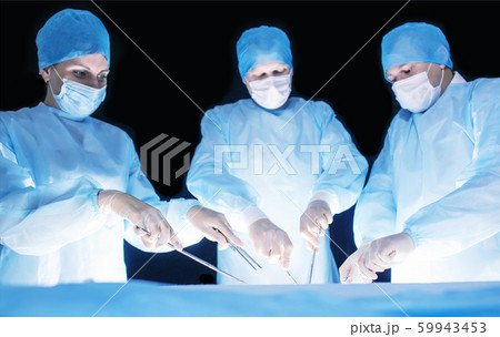 Three surgeons, a man and a woman, perform surgery in the operating room to remove and transplant human organs, resect the stomach and remove the gallbladder, appendicitis 59943453