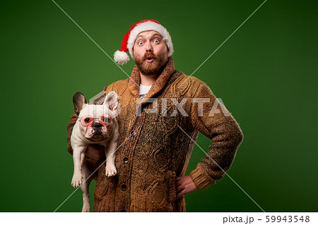 Man in santa hat with bulldog in glasses on empty green background Man in santa hat with bulldog in glasses on empty green background 59943548