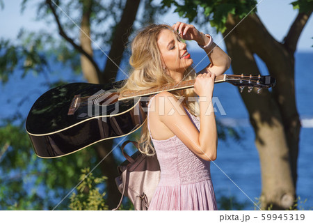 Woman playing acoustic guitar in park Woman playing acoustic guitar in park 59945319
