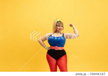 Young caucasian plus size female model's training on yellow background Young caucasian plus size female model's training on yellow background 59946197