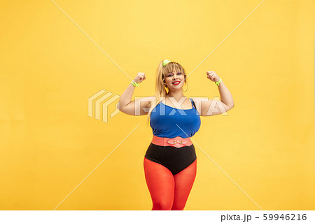Young caucasian plus size female model's training on yellow background Young caucasian plus size female model's training on yellow background 59946216