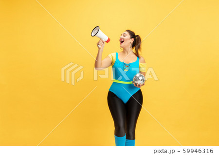 Young caucasian plus size female model's training on yellow background 59946316