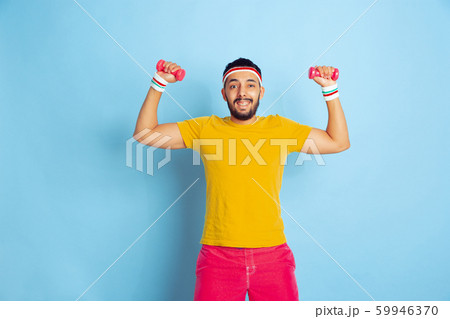 Young caucasian man in bright clothes training on blue background 59946370