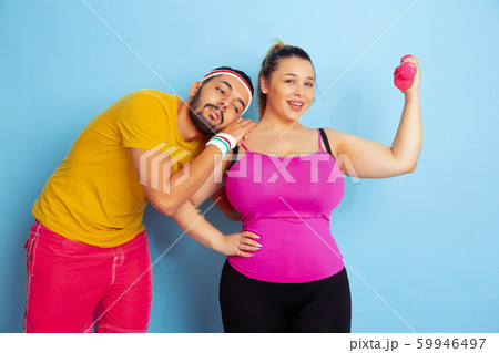 Young pretty caucasian couple in bright clothes training on blue background 59946497
