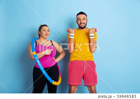 Young pretty caucasian couple in bright clothes training on blue background 59946585