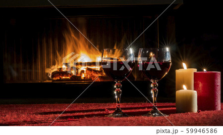 Two glasses with red wine against the background of the fireplace where the fire is burning 59946586