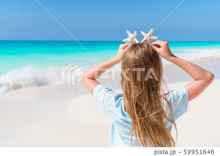 Adorable little girl with starfish on white empty beach Adorable little girl with starfish on white empty beach 59951646