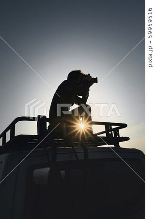 Photographer takes pictures standing on car roof 59959516