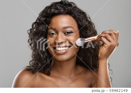 Attractive black girl using brush tool, applying blush on face 59962149