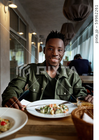 young african american man is eating in a restaurant young african american man is eating in a restaurant 59962261