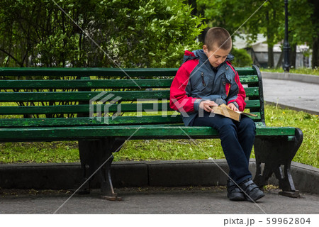 Horizontal image of boy reading a book on bench Horizontal image of boy reading a book on bench 59962804