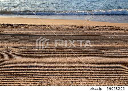 Beach line with sea, waves and sand lined by cleaning machine 59963296