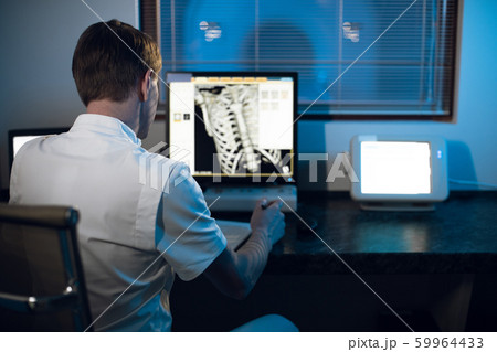 in medical laboratory patient undergoes MRI or CT scan process under Supervision of Radiologist in Control Room, He Watches Procedure and Monitors skeleton and ribs of the patient 59964433