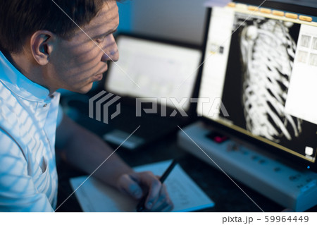 in medical laboratory patient undergoes MRI or CT scan process under Supervision of Radiologist in Control Room, He Watches Procedure and Monitors skeleton and ribs of the patient 59964449