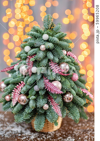Beautiful small Christmas tree on wooden table. Happy mood. Garland lamp bokeh on background Beautiful small Christmas tree on wooden table. Happy mood. Garland lamp bokeh on background 59965208