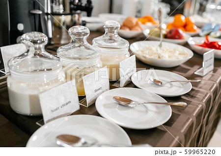 Saucers with spoons in the foreground. Honey, condensed milk, yogurt. Breakfast buffet in hotel. Saucers with spoons in the foreground. Honey, condensed milk, yogurt. Breakfast buffet in hotel. 59965220