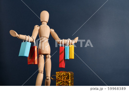 Cheerful happy shopaholic wooden doll with lots of shopping bags on arm 59968389