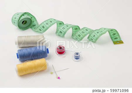 Sewing accessories on a white background. Centimeter tape, spools of thread, pins Sewing accessories on a white background. Centimeter tape, spools of thread, pins 59971096