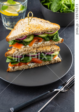 Sandwiches with cream cheese, salmon and spinach on a dark background. Sandwiches with cream cheese, salmon and spinach on a dark background. 59976873
