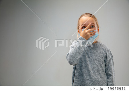 Caucasian girl wearing the respiratory protection mask against air pollution and dusk on grey studio background 59976951