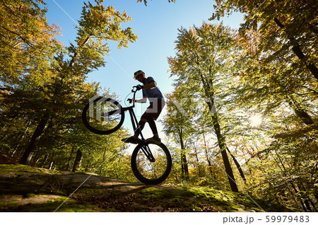 Sportsman cyclist balancing on back wheel on trial bicycle 59979483