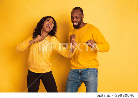 Young emotional african-american man and woman on yellow background 59980046