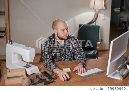 Man on the computer makes out the delivery of the online store. Working with sewing machine in a 59980940