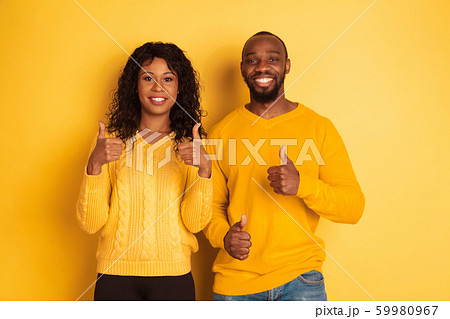 Young emotional african-american man and woman on yellow background 59980967
