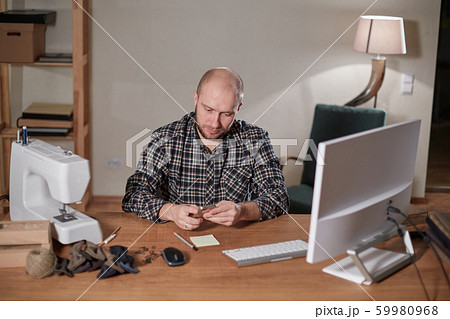 Man on the computer makes out the delivery of the online store. Working with sewing machine in a 59980968