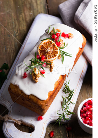Fruit cake dusted with icing, nuts, kernels pomegranate and dry orange close-up. Christmas and Winter Holidays homemade cake 59983091