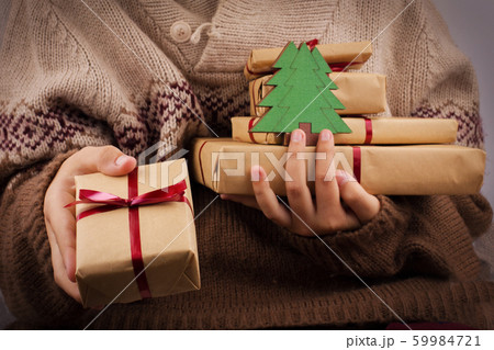 Hand holds out a gift box. Girl in a knitted Hand holds out a gift box. Girl in a knitted 59984721