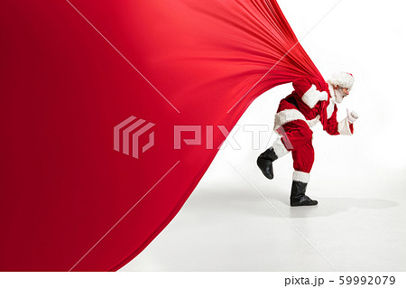 Santa Claus pulling huge bag full of christmas presents isolated on white background 59992079
