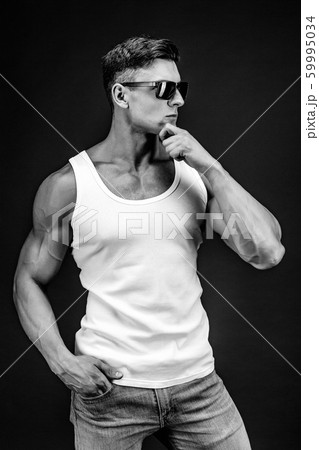Handsome muscular man in dark glasses and a white shirt. 59995034
