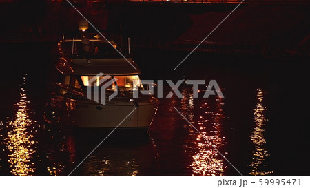 Luxurious modern private yacht and boat at the pier at night. Colorful lights of city glow shine 59995471